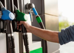 Hand of unrecognizable client taking gas nozzle from pump while visiting filling station on sunny day